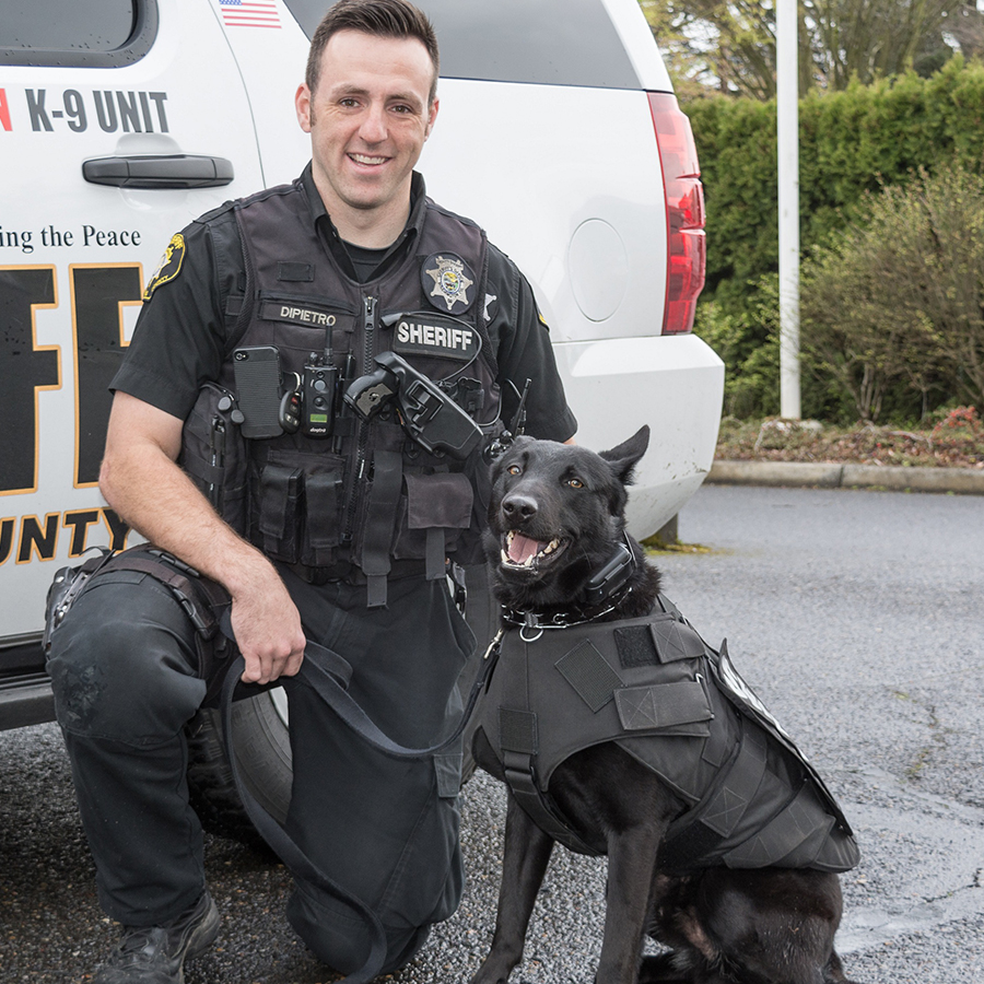 Sheriff deputy kneeling next to his police dog